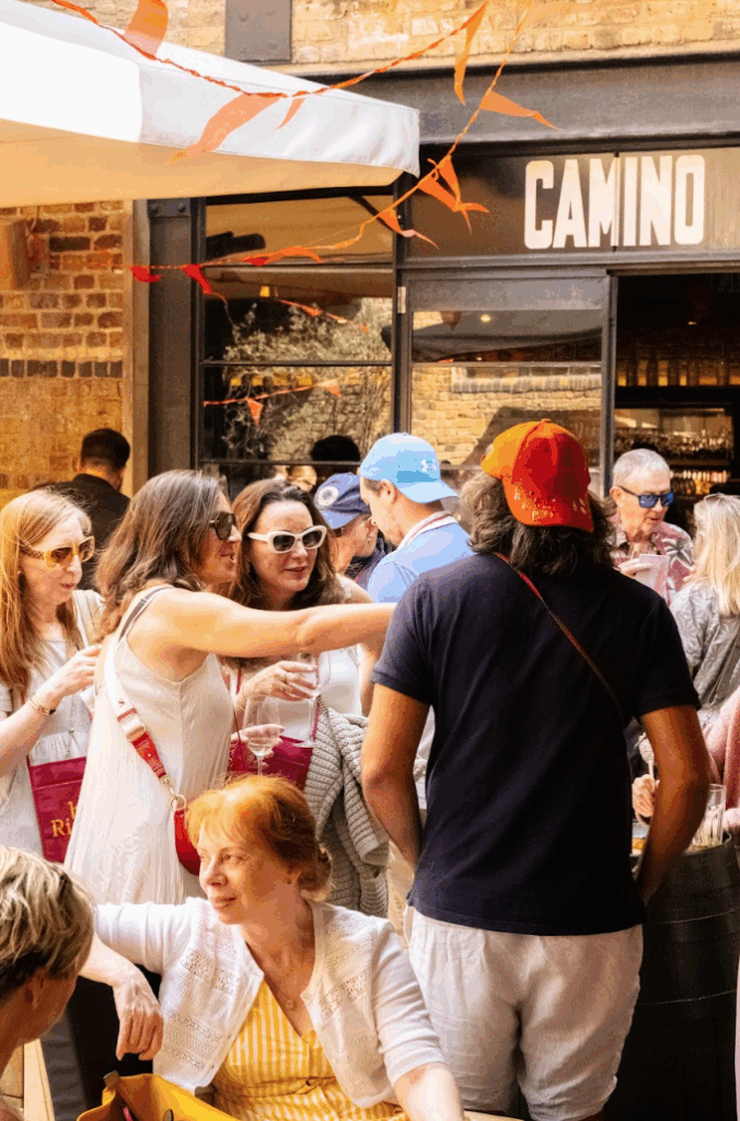 A group of people socializing outdoors in front of a restaurant called 